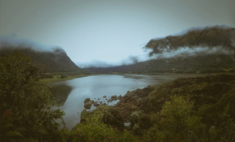 fog hanging over the river and mountains near water