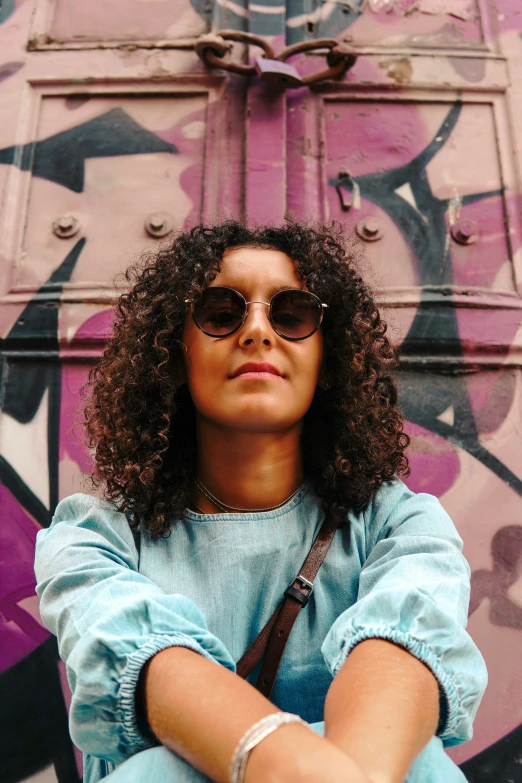 a woman with her arms crossed and wearing sunglasses