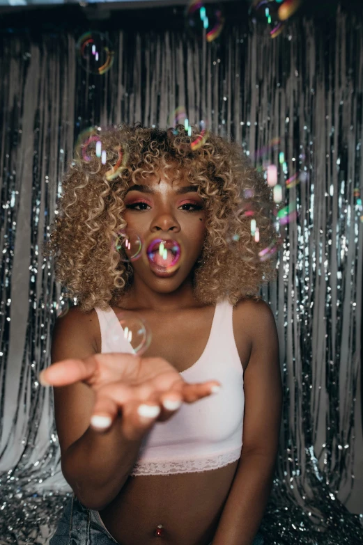 a woman blowing bubbles while standing in front of curtain