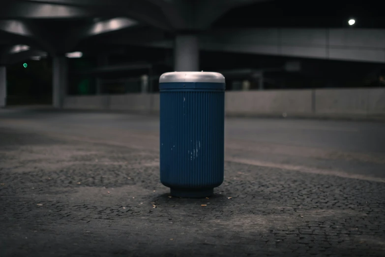 a blue trash can sitting on the side of the road