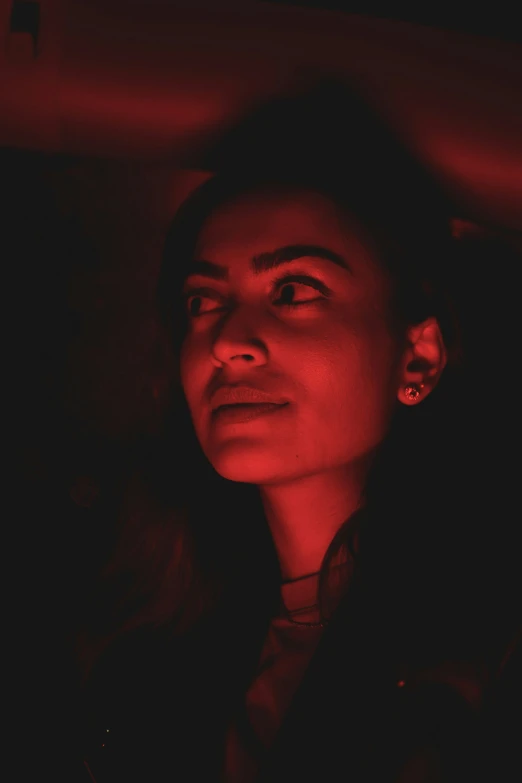 a woman with ear ring sitting in the dark