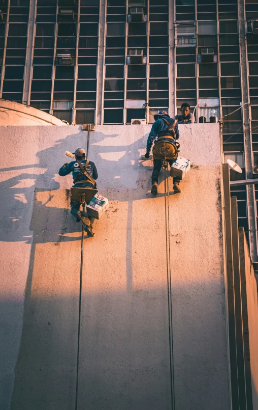 a view of three snow boarders in shadow on the concrete