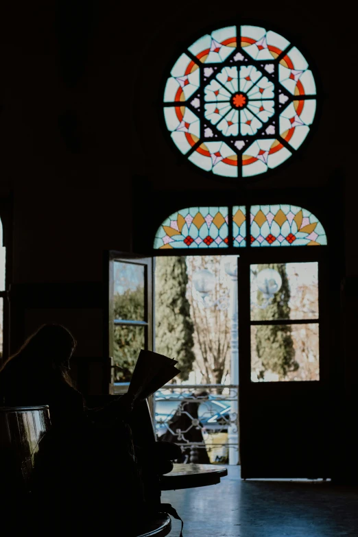 a woman reading in front of a stained glass window