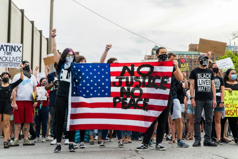 protesters with signs in front of a crowd holding their arms up