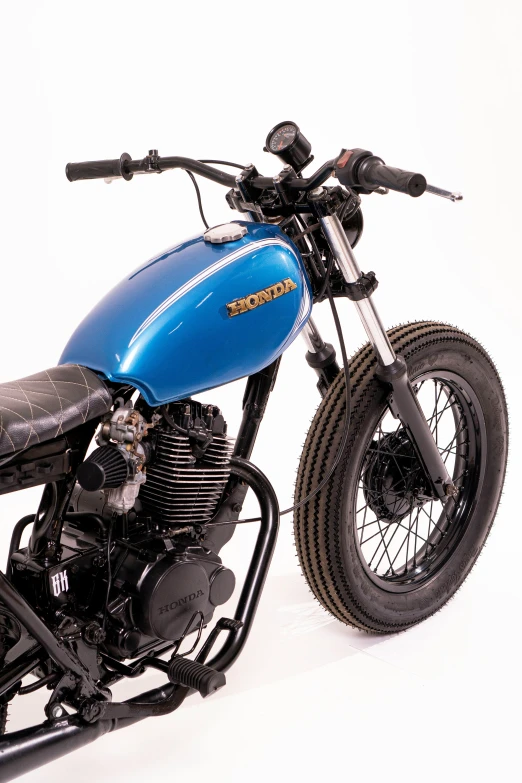 a blue and black motorcycle sitting up against a white background