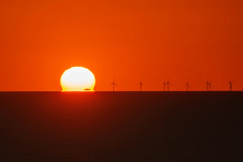 wind turbines are in the distance with an orange sky