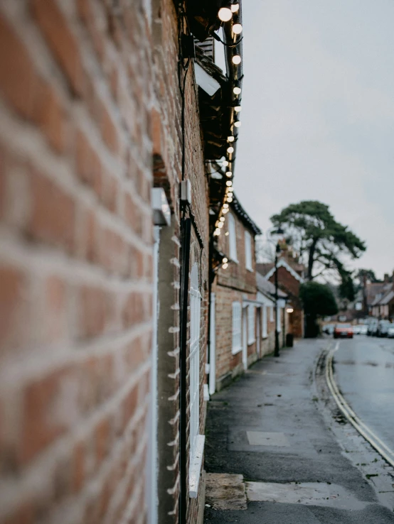 lights hanging from the side of brick buildings on a street