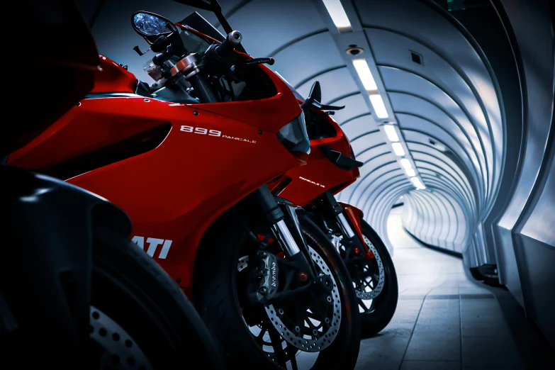 a very red motorcycle parked in a narrow tunnel