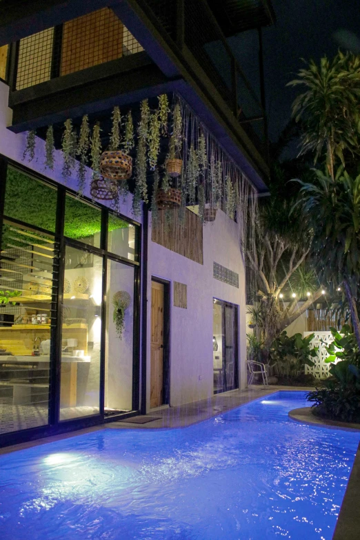 a blue lit pool sits in front of a building