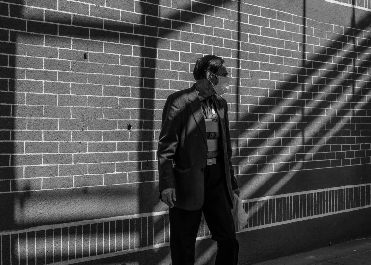 a man standing by a brick wall in the shadows