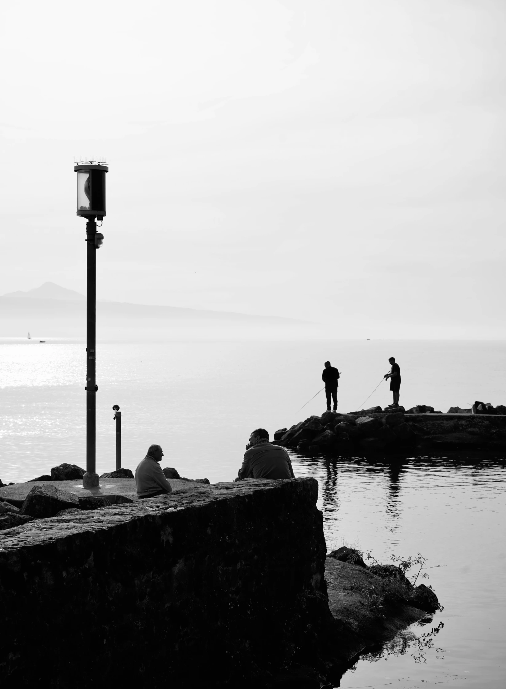 two people fishing off of a dock near the ocean