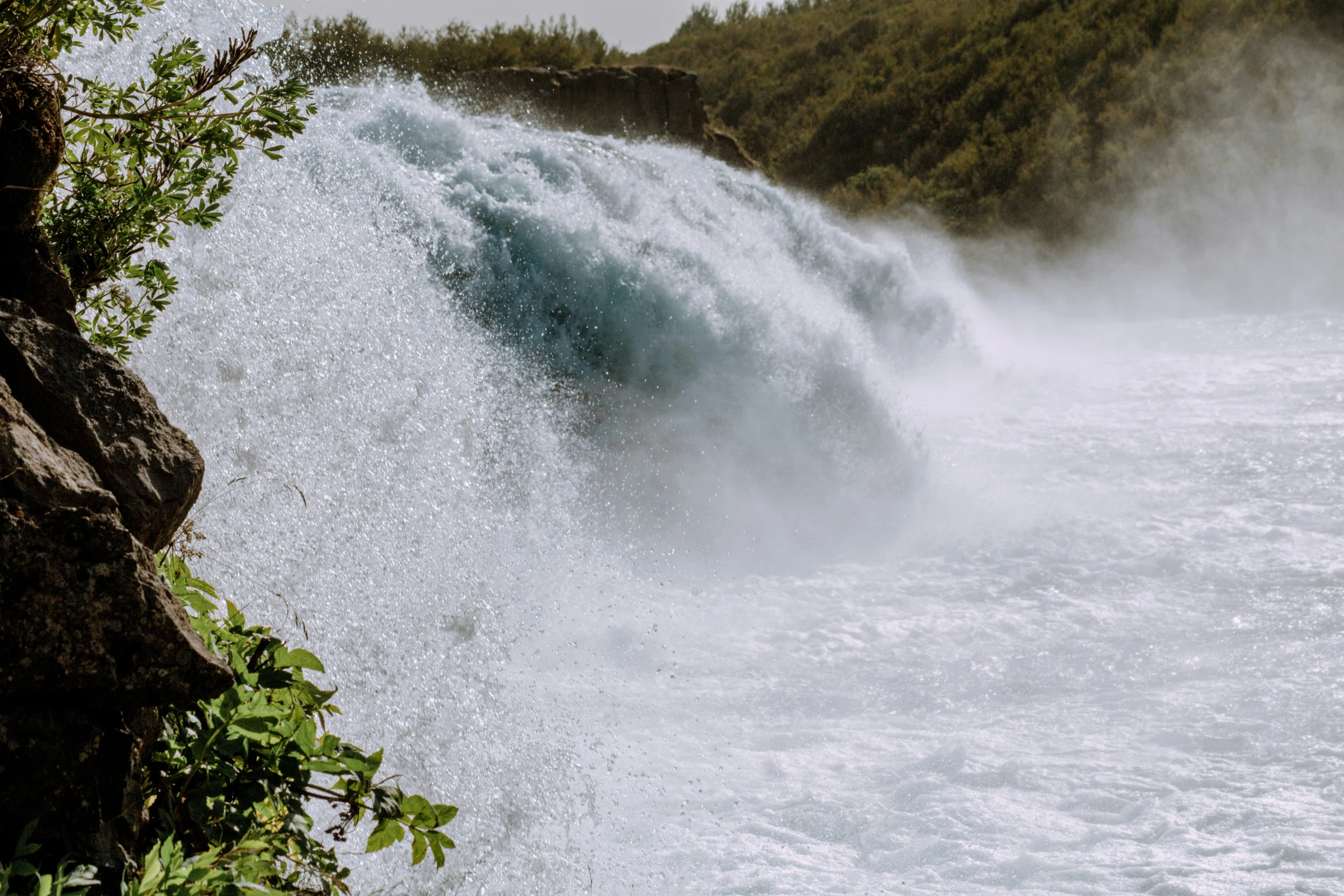 a waterfall pouring down with some trees on the side