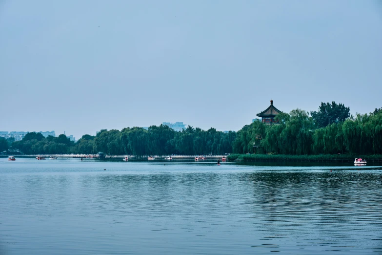 an overcast sky hangs over a lake and trees