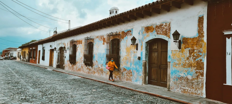 a man with a backpack walks down a cobblestone road