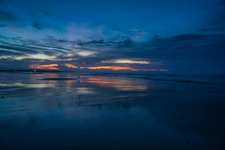 a beach filled with water at sunset and lots of clouds