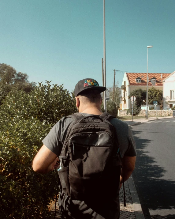 the man is walking towards his house holding onto a backpack