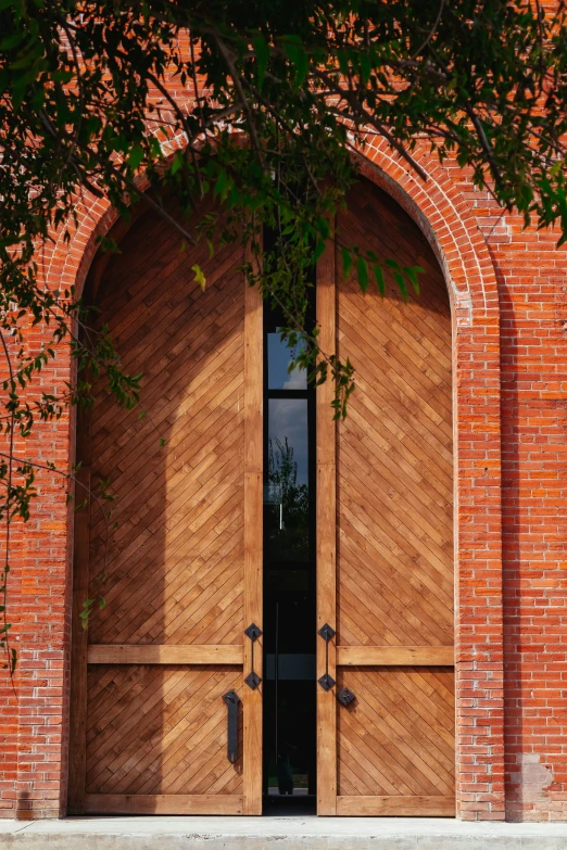 large wooden doors with black handles in front of a red brick building