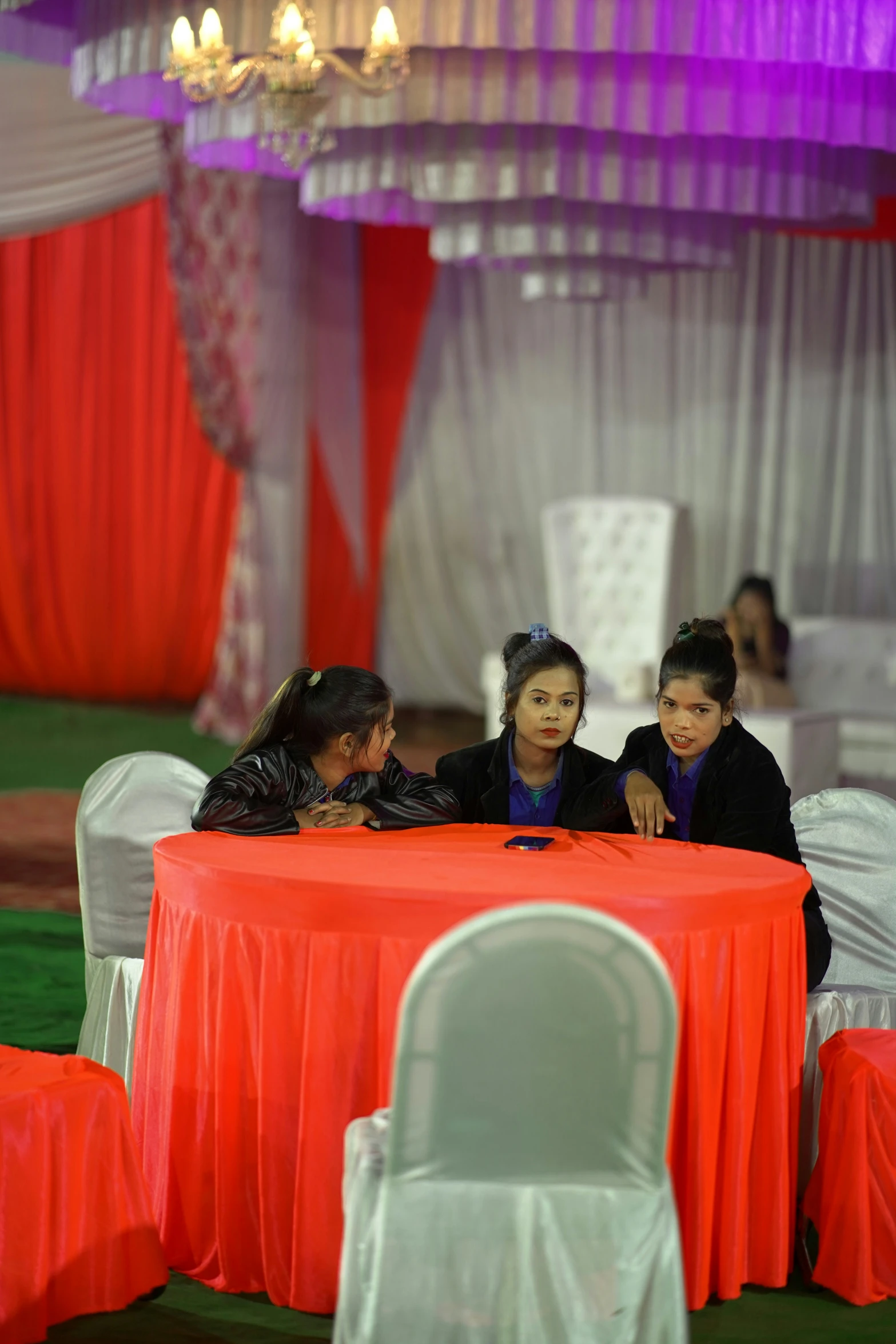 several people seated around a red cloth table