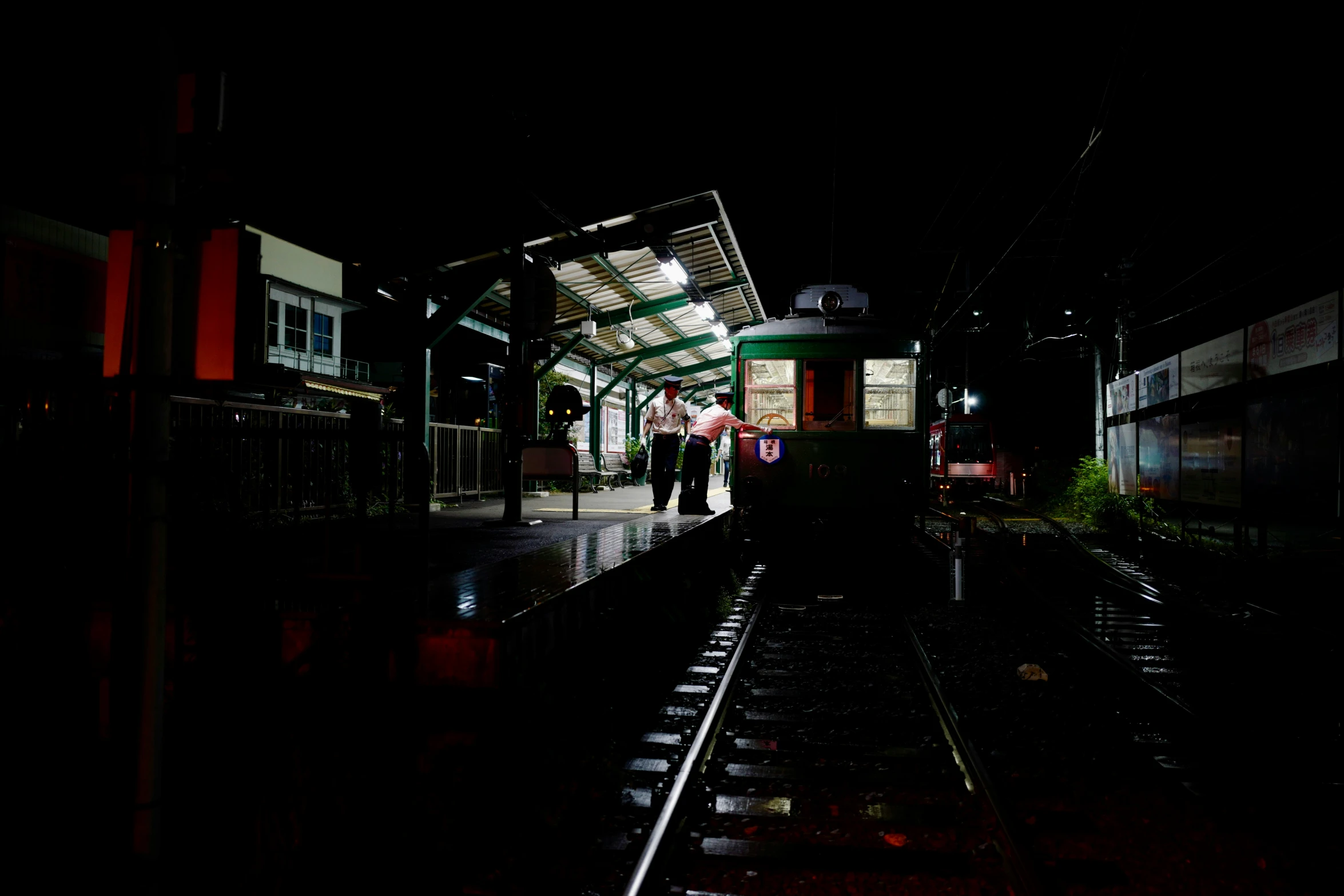 two people standing at a train station with lights on