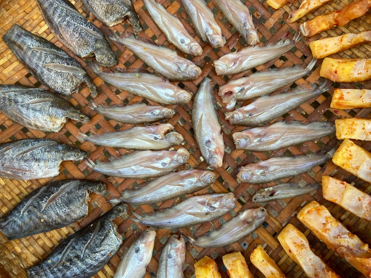 several fish laying on a grill with potatoes