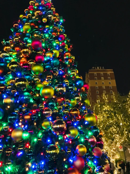 a large christmas tree is covered in multicolored balls