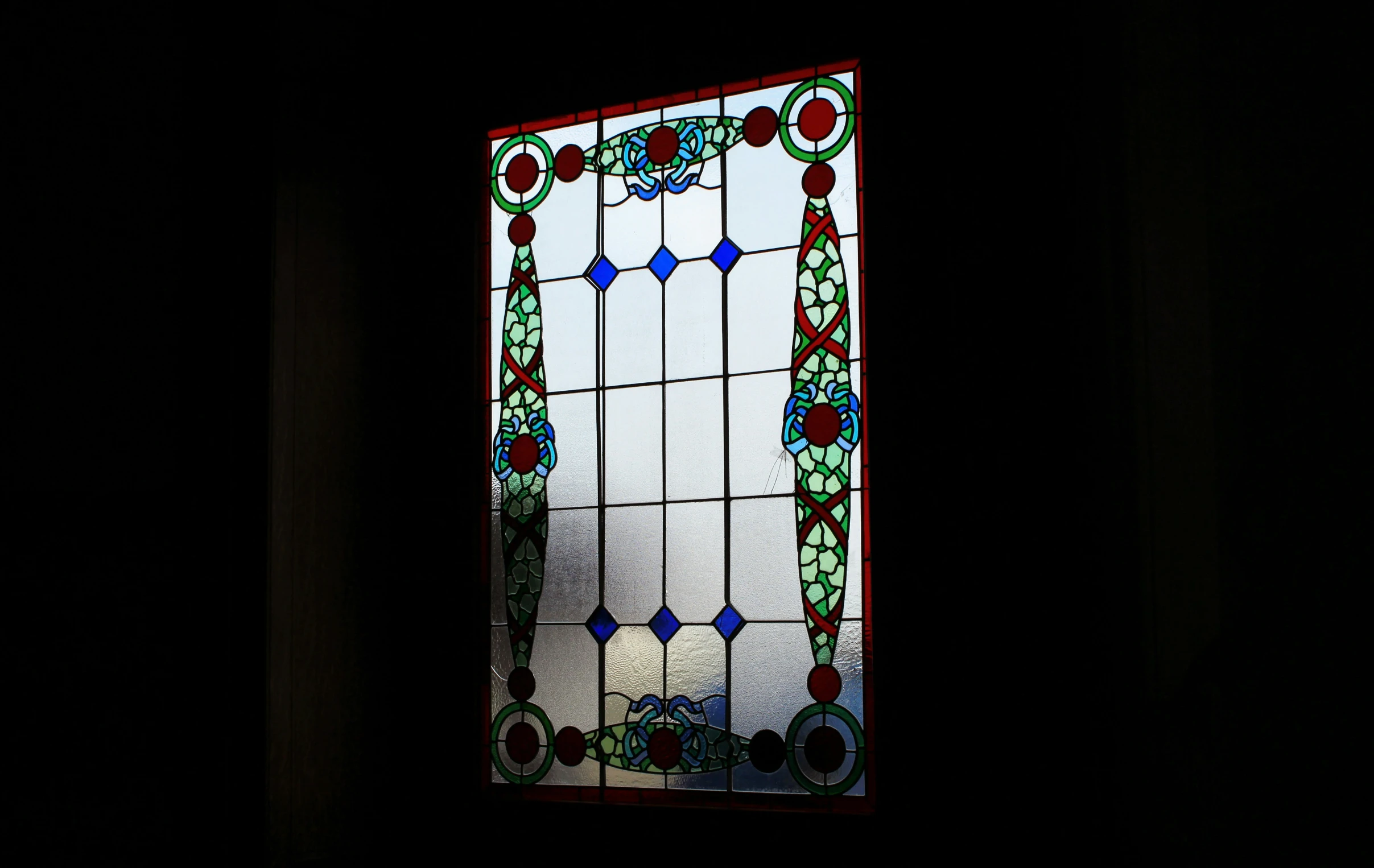 a dark room with a large glass window that has designs on it