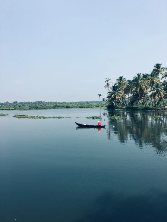 a long boat with people in it sailing along a large body of water