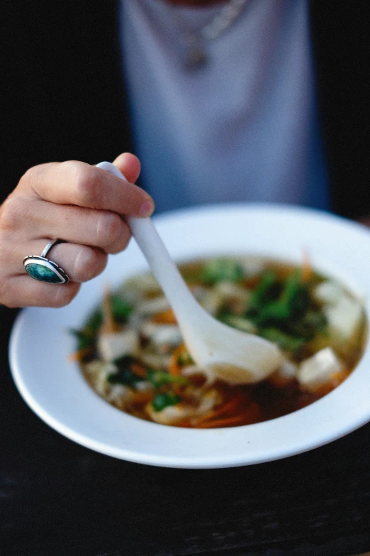 the woman is eating soup with a spoon in her bowl