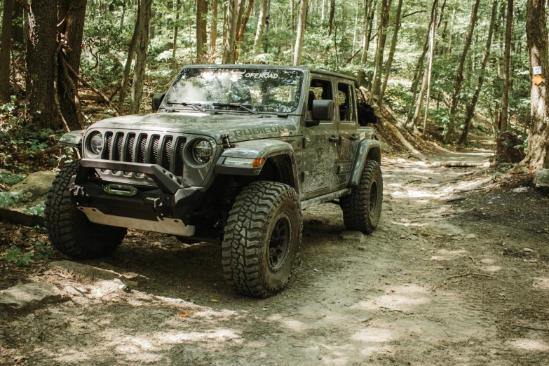 a gray jeep parked in the middle of a forest