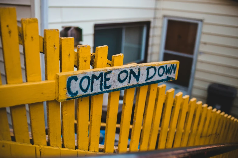 a wooden sign that reads come on down sits in the middle of a yard