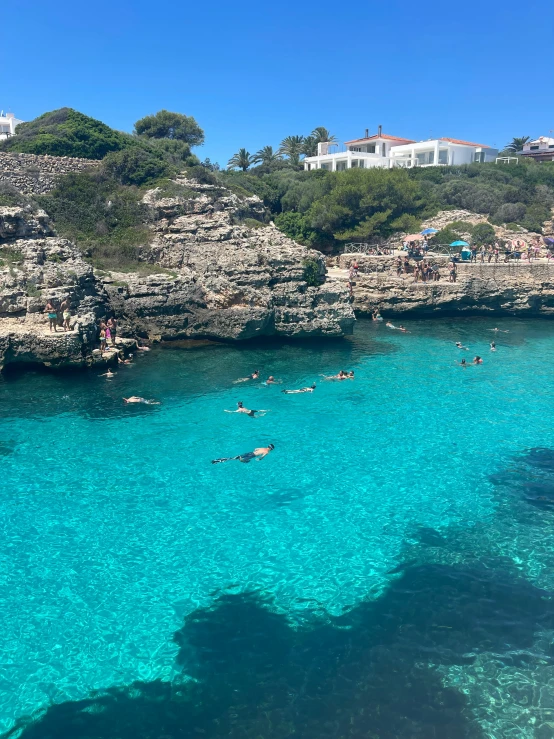 the blue waters are crystal clear as swimmers swim in it