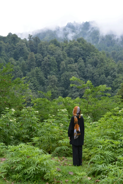 a man in a black jacket and hat is walking in the middle of the woods