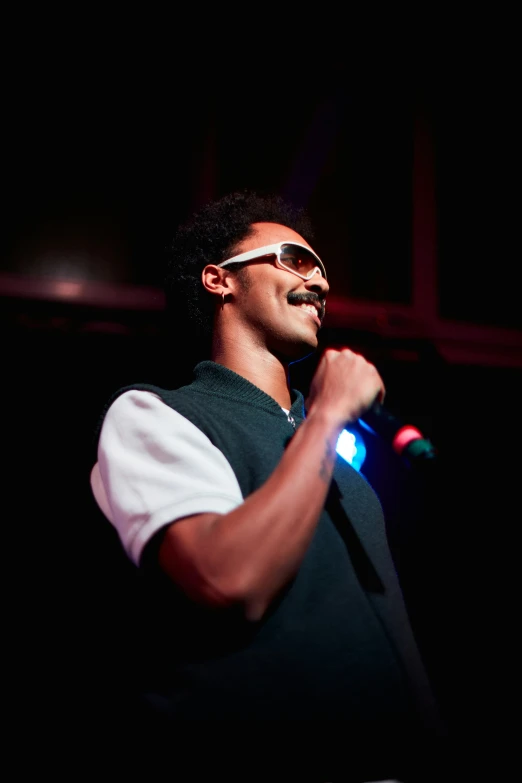 a man with a beard, sunglasses and some microphones