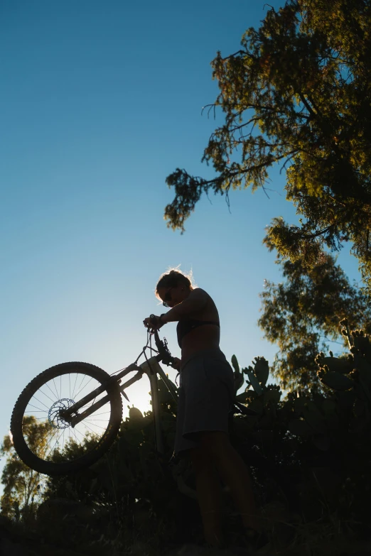 the man in shorts is holding his bike up