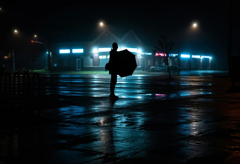 a dark street at night with a person holding an umbrella