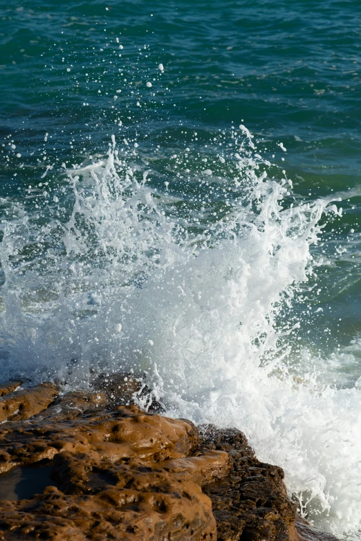 an ocean wave hitting the rocks near the beach