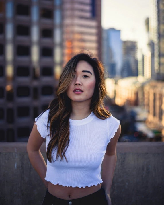 a woman in white top and black pants with buildings behind her