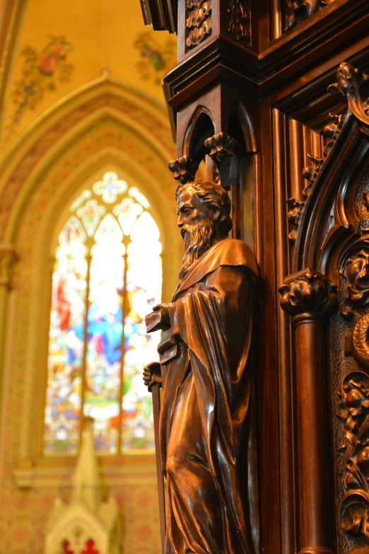 a statue of an saint on a large wooden surface next to a window