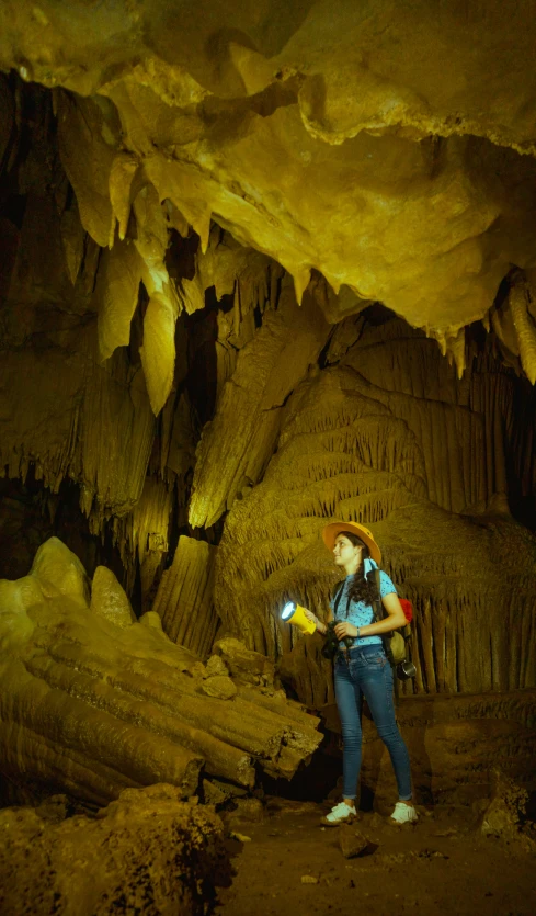 a woman holding a light standing inside of a cave