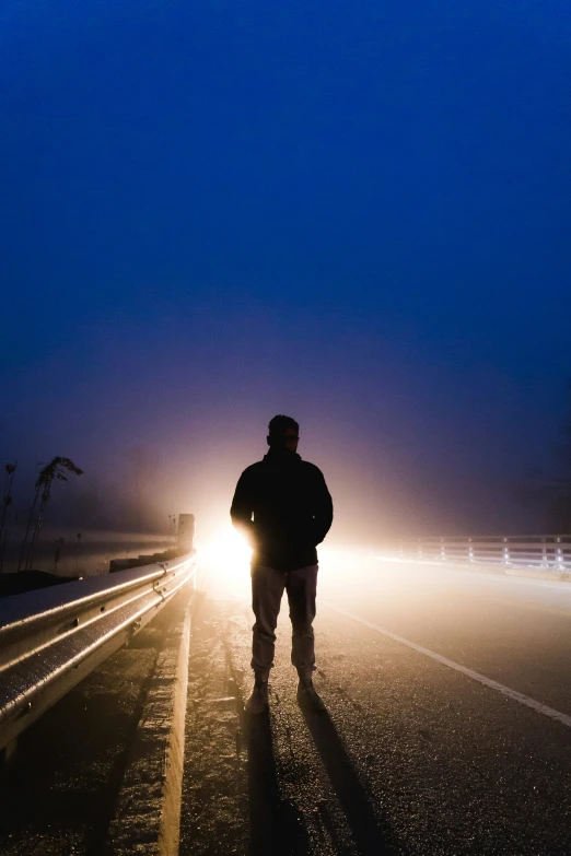 a man walking in the dark on a highway