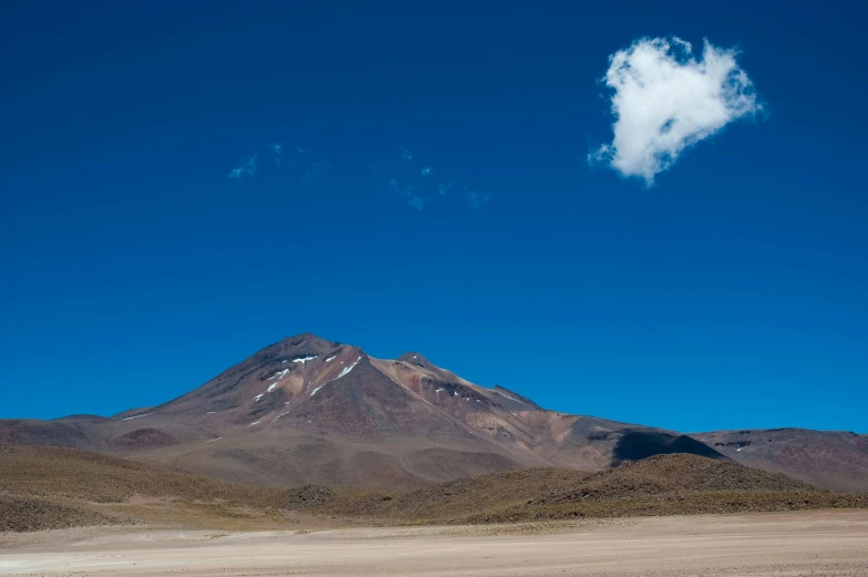 some clouds are floating in the blue sky above a mountain