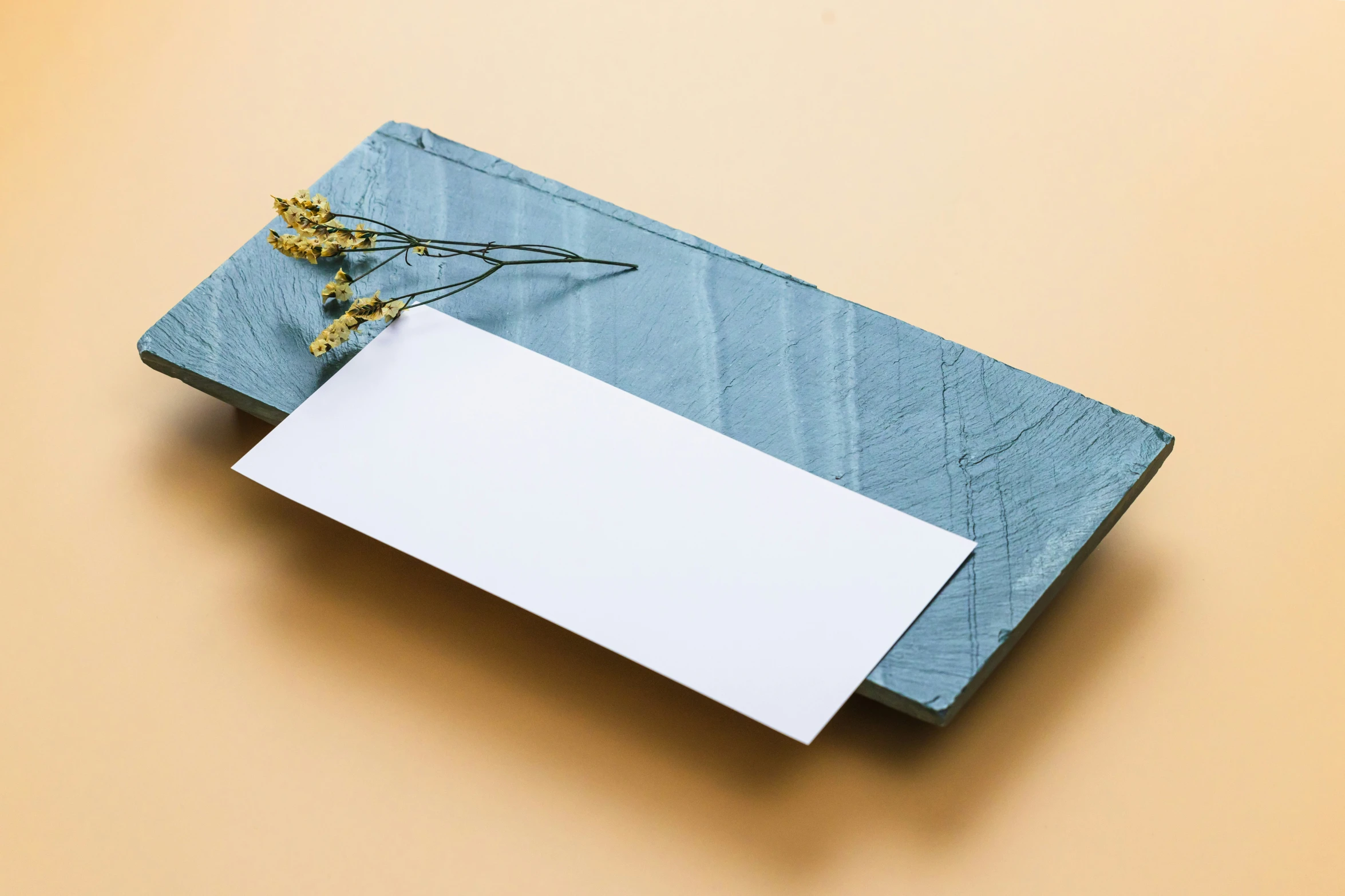 a white envelope and some yellow flowers on a tan background