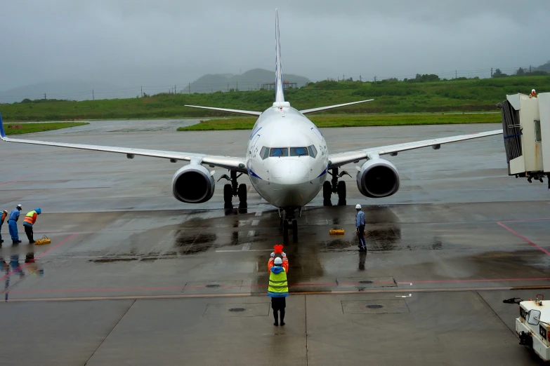 men work on the side of an airplane at an airport