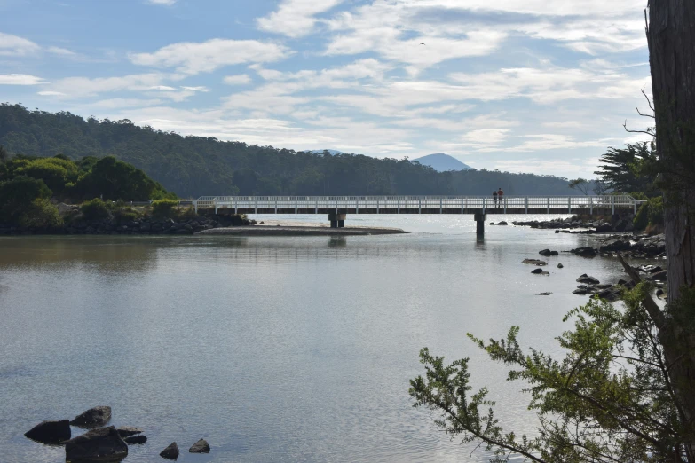 the water is calm and serene with a bridge spanning over it