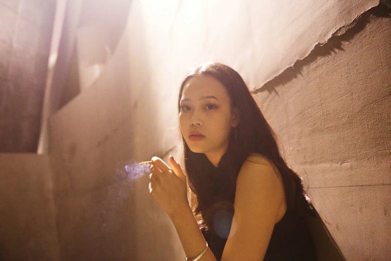 a woman holding a cup in her hands and sitting against a wall