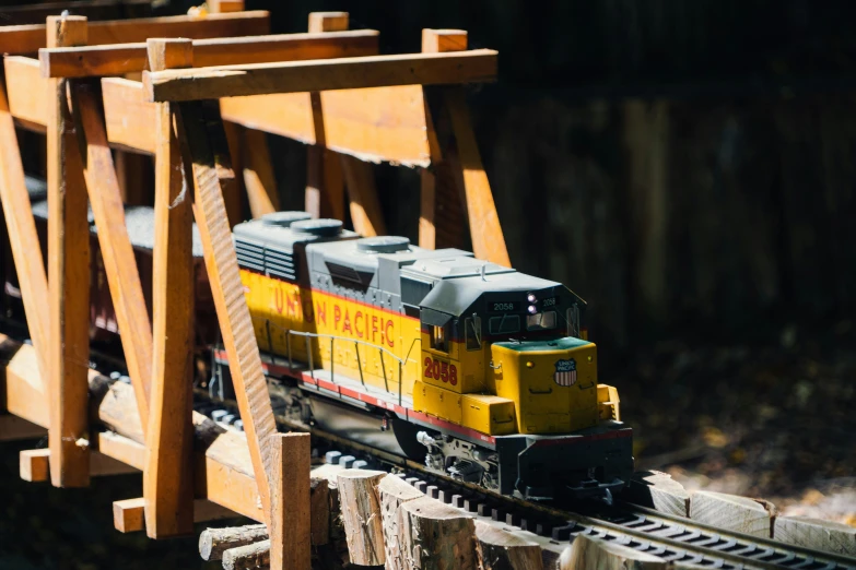 yellow train on track next to large wooden structure