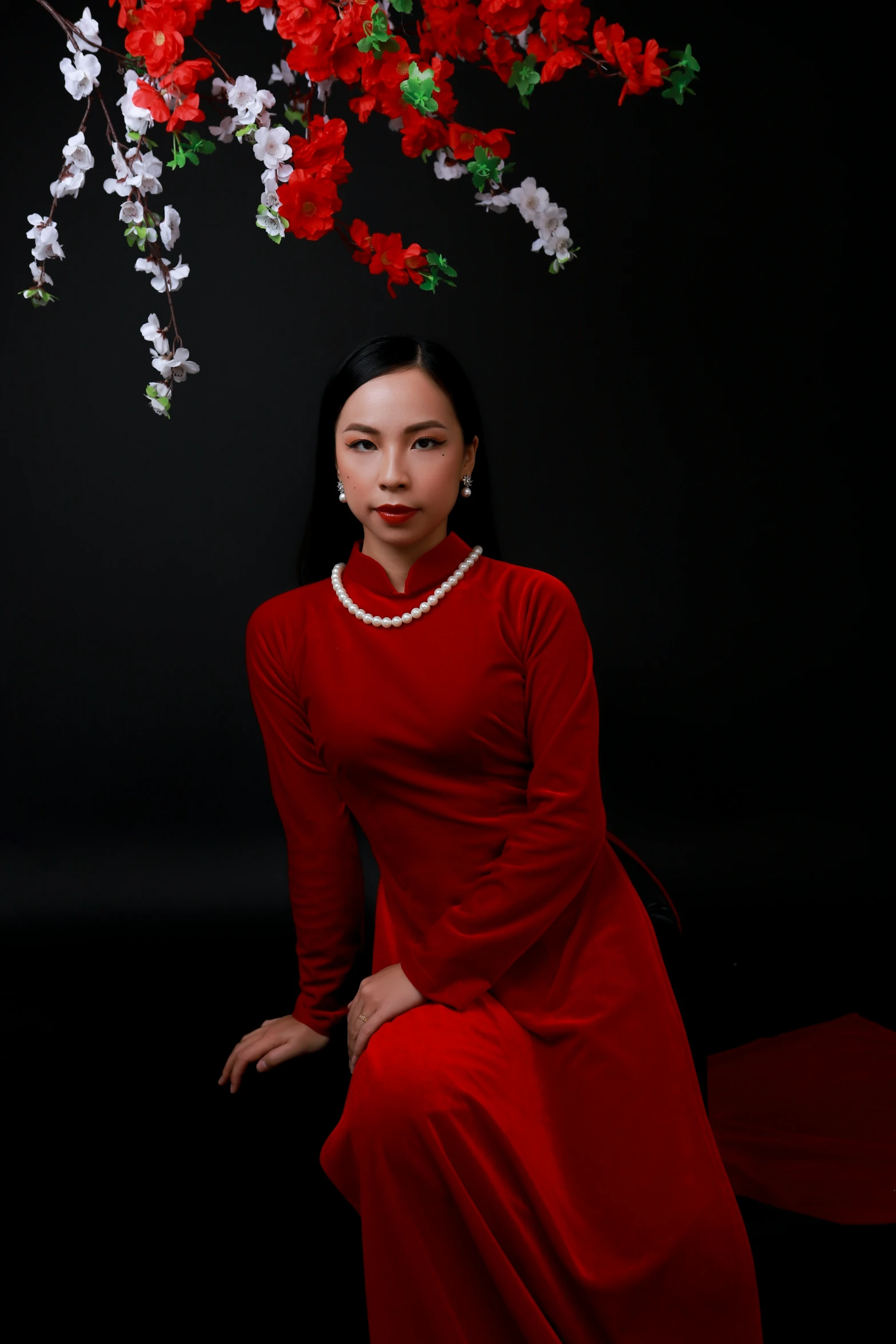 a woman in a red dress sitting under a tree of flowers