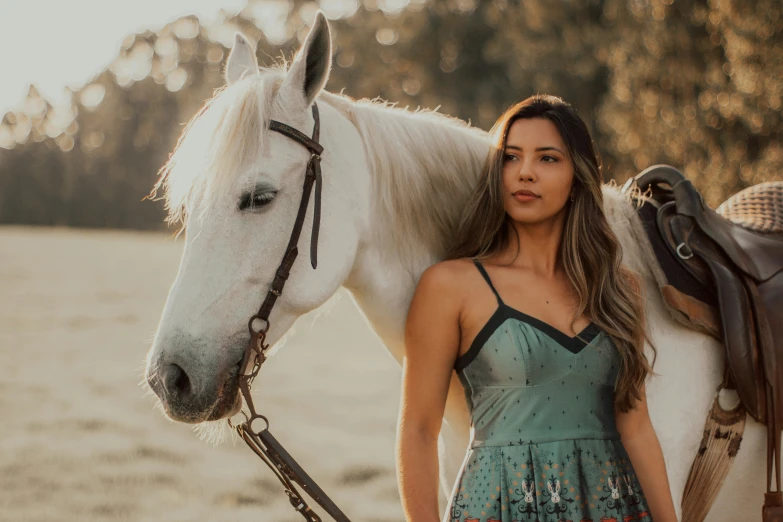 woman with white horse on dirt field at sunset