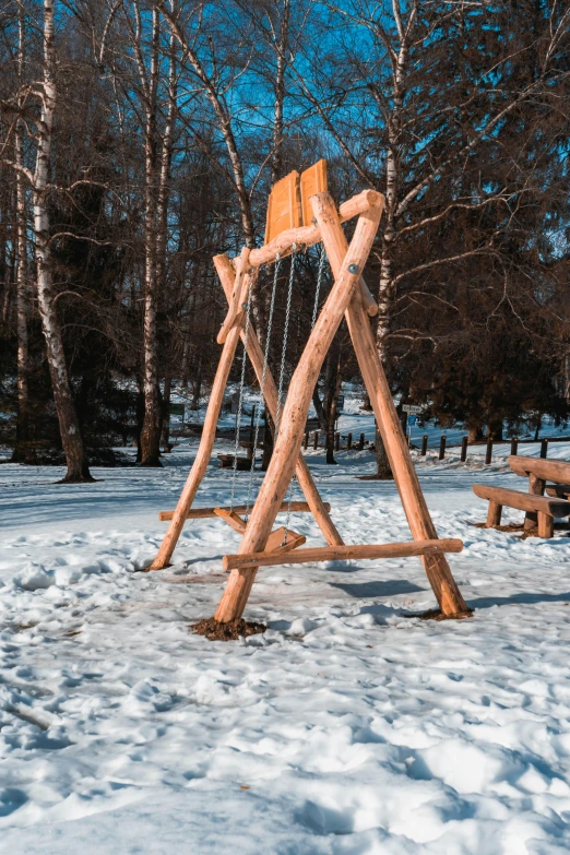 an image of a wooden swing set in the snow