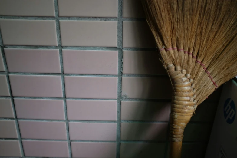 a broom is next to a toilet in a restroom